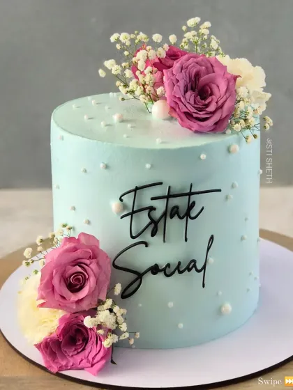 A full view of the pastel blue "Estate Social" cake, showing its clean lines and simple, elegant floral arrangement.