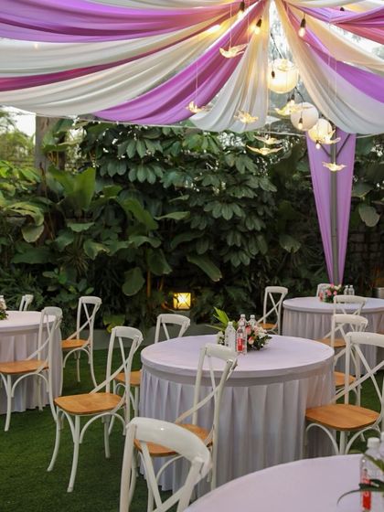 A close-up of the guest seating at a baby shower in The Backyard. The purple and white color scheme is carried through to the table settings, creating a cohesive look.