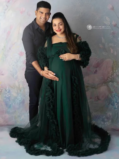 A beautiful couple's portrait in a rich green gown. The way they hold each other shows their strong bond as they prepare to welcome their baby.