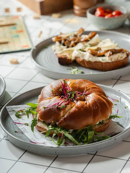A beautiful breakfast spread featuring our pretzel bagel sandwich and a wild mushroom toast, perfect for sharing or for a very hungry individual.