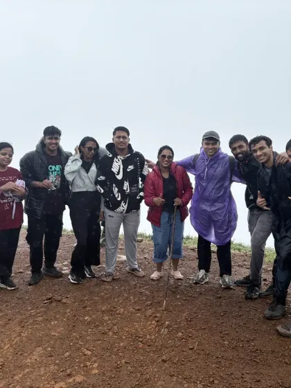 The group poses for a photo at the summit, celebrating their successful climb despite the rainy weather.