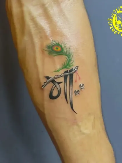 A creative and colorful tribute to a mother, combining the Hindi script for "Maa" with a peacock feather, a symbol often associated with Lord Krishna.