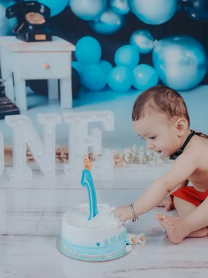 Reaching for the cake, this photo shows the birthday boy's excitement and the fun, interactive nature of a cake smash session.
