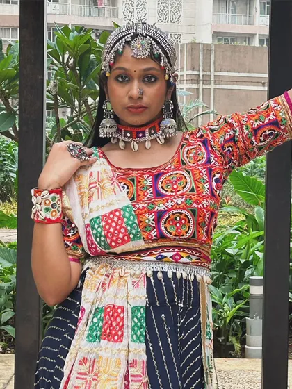 A close-up look at the beautifully embroidered blouse and accessories. The patchwork design and mirror work are hallmarks of traditional Gujarati craftsmanship.
