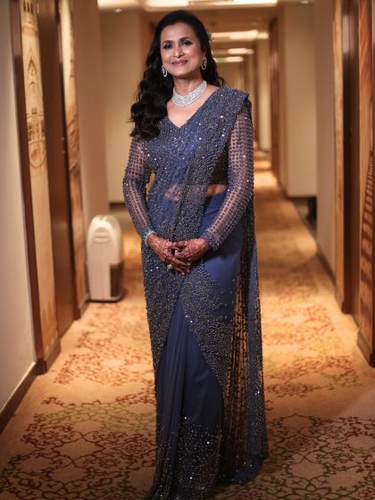 A full-length shot showing her complete, elegant look for the Sangeet. The makeup is polished and glamorous, perfectly complementing her sparkling navy saree.