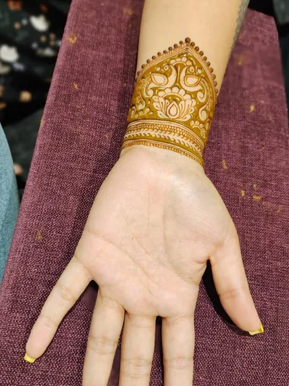 This trendy wrist cuff design is a favorite among guests who want something stylish and quick. It features delicate peacock and lotus details, offering the elegance of traditional henna in a modern, bracelet-like form.