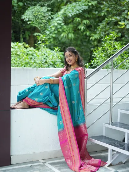 A candid and happy portrait of a client wearing a rented Nauvari saree. She is sitting comfortably on a ledge at the outdoor shoot location, with lush greenery providing a serene and natural background.