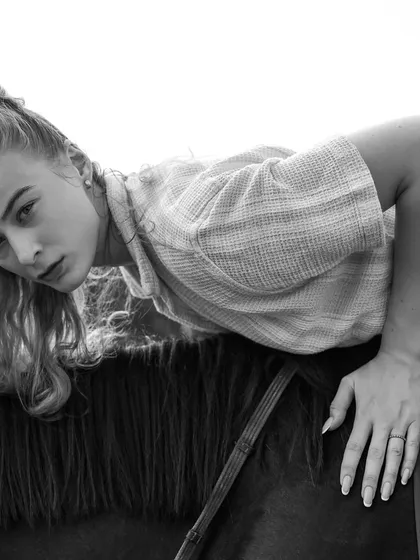 A creative, black and white shot of a model lying across the horse's saddle. This artistic composition highlights the trust between human and animal, ideal for evocative photoshoots.