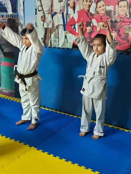 Young students in their karate gi, raising their arms during a warm-up exercise. We start every class with movements designed to prepare the body for training.