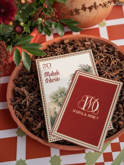 Custom wedding invitations and stationery for the 'Mughal Garden' theme, displayed in a terracotta bowl of star anise, connecting the design to fragrant, traditional elements.