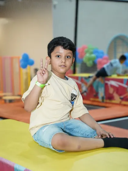 A young boy gives the peace sign while sitting in our trampoline park. It's a place to chill out and have fun.