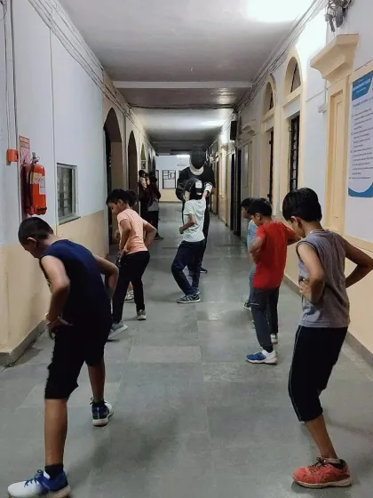 Young fencers participate in a dynamic warm up session. These exercises are designed to prepare their bodies for the specific movements required in fencing, focusing on leg strength and flexibility.