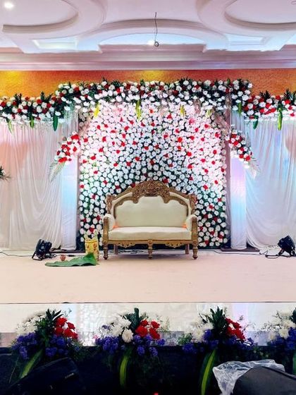 For this indoor wedding reception, I created a wide stage with a backdrop of dense red and white flowers. The design is framed by a floral arch and complemented by elegant white draping and multiple spotlights to highlight the intricate details.