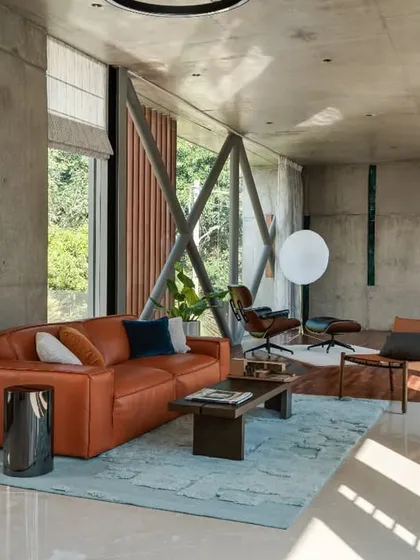 Natural light floods this living space, highlighting the raw concrete walls and ceiling. We introduced pops of color with contemporary furniture, creating a vibrant yet sophisticated atmosphere within the minimalist shell.