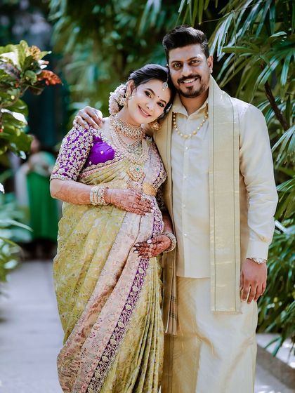 A happy portrait of the expecting couple. Her radiant smile is matched by the beauty of her custom-designed saree and his elegant traditional wear.