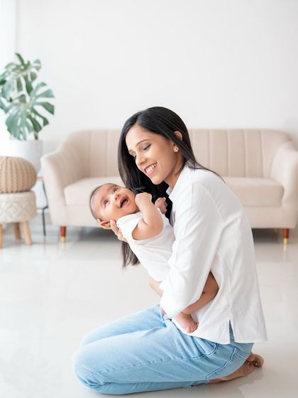 A mother's joy is so evident as she holds her smiling baby in her arms.