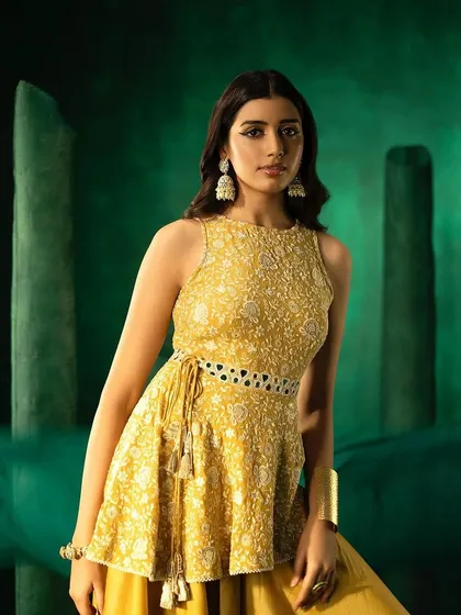 A close-up of a golden yellow peplum top from 29 India, highlighting the intricate chikankari embroidery.