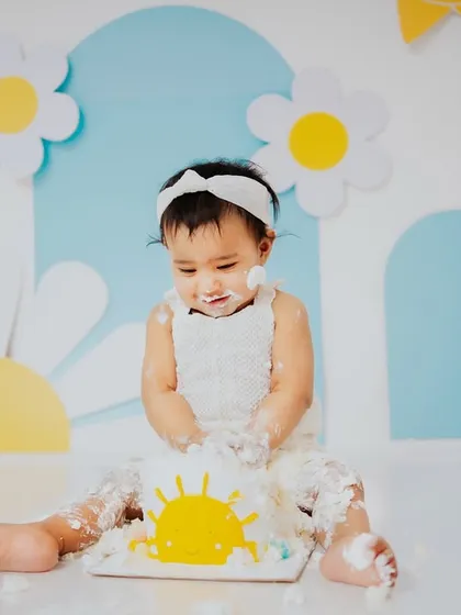 Getting right into the fun. This shot shows the beginning of the mess, as she curiously explores her sunshine cake during her first birthday photoshoot.