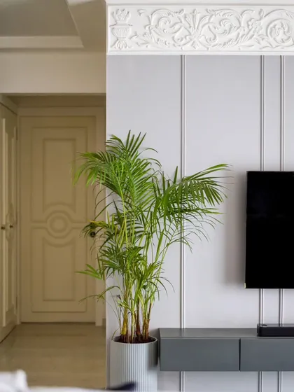 A closer look at the TV wall, showing the contrast between the smooth, muted grey panels and the intricate white moulding.