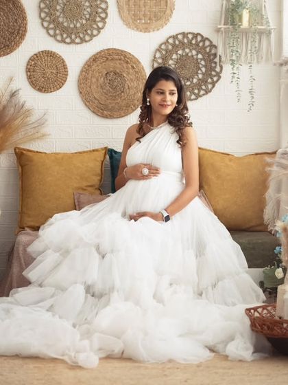 A wide shot showing the full splendor of the white ruffled gown against our popular boho backdrop with pampas grass and wicker decor.