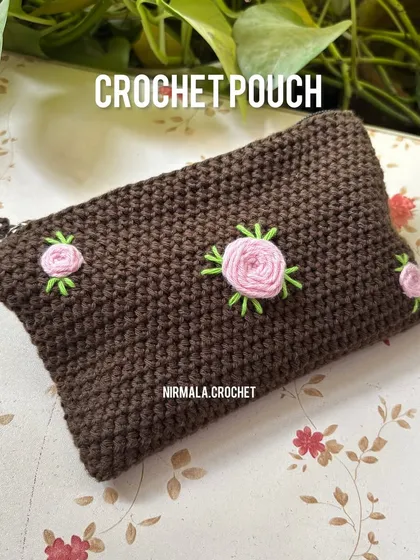 A clear shot of the brown crochet pouch with its lovely rose embroidery. The simple, tight stitches create a solid fabric to protect your belongings.