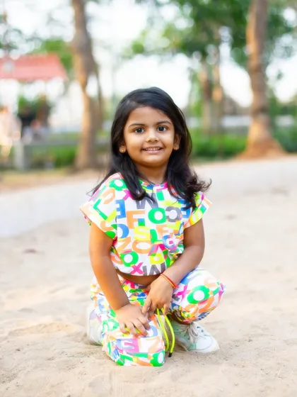A bright, happy portrait in the sand. The colorful outfit and her direct, smiling gaze make this a vibrant and engaging photo that captures her playful nature.