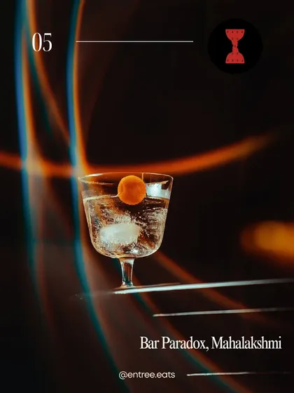 A moody, atmospheric shot of a classic cocktail at Bar Paradox. The dramatic lighting with light streaks creates a futuristic, intriguing vibe, perfect for a bar with a unique concept.