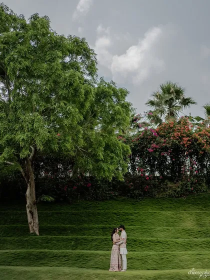 A wide-angle shot showing the couple surrounded by the vast, beautiful green landscape. It's about capturing love in nature.