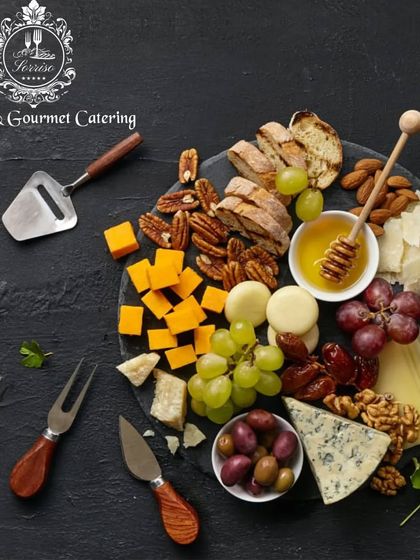 A classic charcuterie board from a top-down perspective. This shot highlights the perfect pairing of cheeses, nuts, dried fruits, and honey, complete with specialized cheese knives for serving.