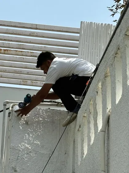 My team member works carefully on a narrow ledge to install a camera, showcasing our commitment to securing even the most difficult-to-reach areas of a property.