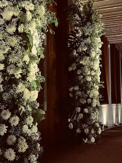 Grand floral pillars at the entrance of an anniversary party, creating a lush and romantic welcome for guests.