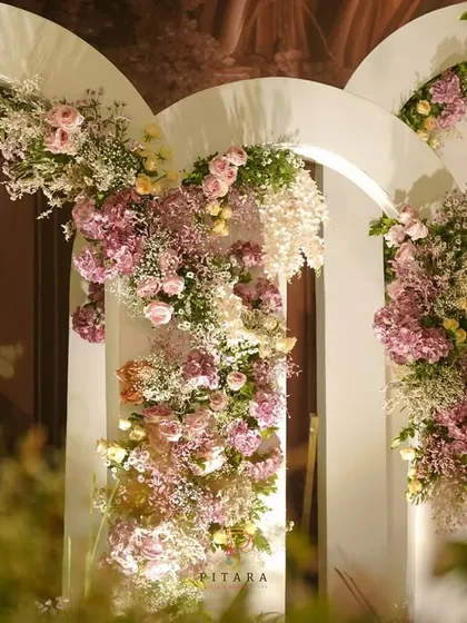 We love creating picture-perfect moments. This backdrop of layered white arches, adorned with cascading florals in soft pastel shades, served as a romantic and dreamy photo corner for guests.