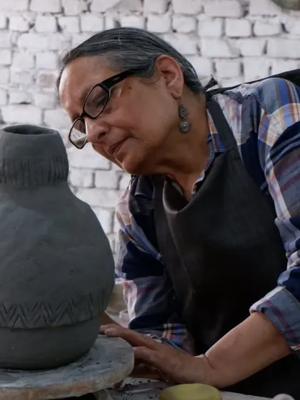 A student admires her large, hand-built vase with incised patterns. This piece will look incredible after the Raku firing, with smoke highlighting the textures.
