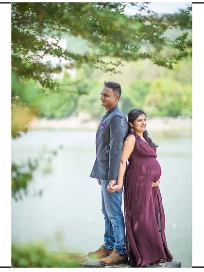 A romantic back-to-back pose by the water, with the couple holding hands.