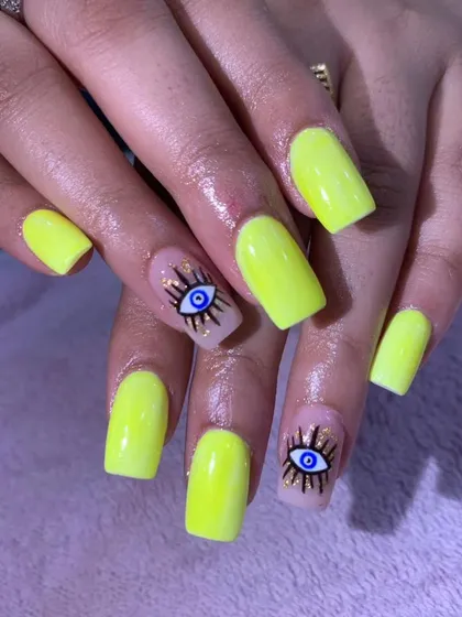 A bright and bold set of neon yellow nails with "evil eye" accent nails for a trendy and protective charm.