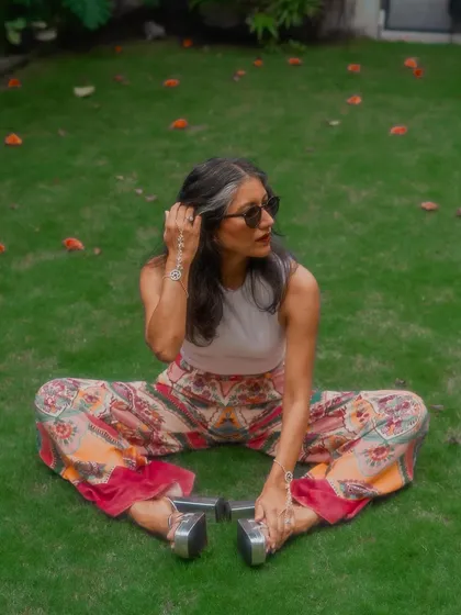 A seated pose showing the flow and vibrant print of the palazzo pants.