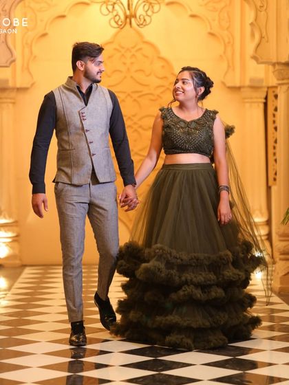 Walking hand-in-hand, this couple shows off their coordinated style. The modern suit on him and the dramatic gown on her are perfect for an indoor pre-wedding shoot with grand architecture.