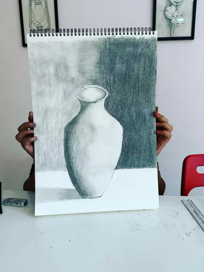 A student holds up their beautifully shaded vase. The dark background really makes it stand out.