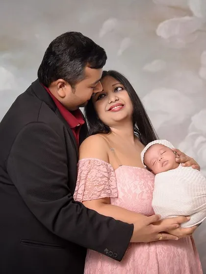 A sweet family portrait with a newborn against a soft, floral painted backdrop. The parents' gentle embrace and loving expressions make this a warm and sentimental keepsake.
