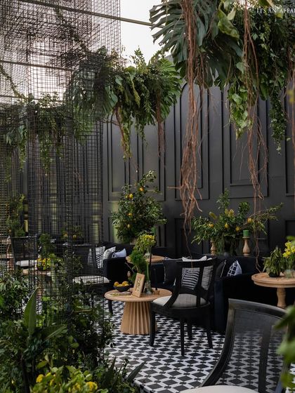 A cozy lounge area within the 'Lemon Garden' theme, featuring black velvet sofas, checkered cushions, and fresh lemon tree arrangements.