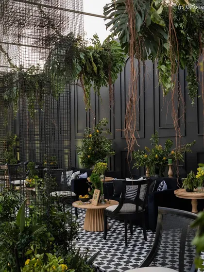 A cozy lounge area within the 'Lemon Garden' theme, featuring black velvet sofas, checkered cushions, and fresh lemon tree arrangements.
