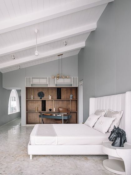 A wider view of the neutral-toned bedroom, showing the integrated study nook. The design maintains a clean, uncluttered aesthetic, with a vaulted ceiling that enhances the sense of space and light.