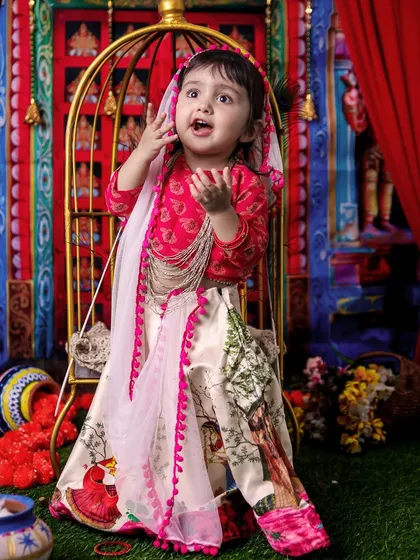 This little Radha looks so expressive, reaching up as if telling a story. The detailed outfit and vibrant background make this a dynamic and engaging portrait.