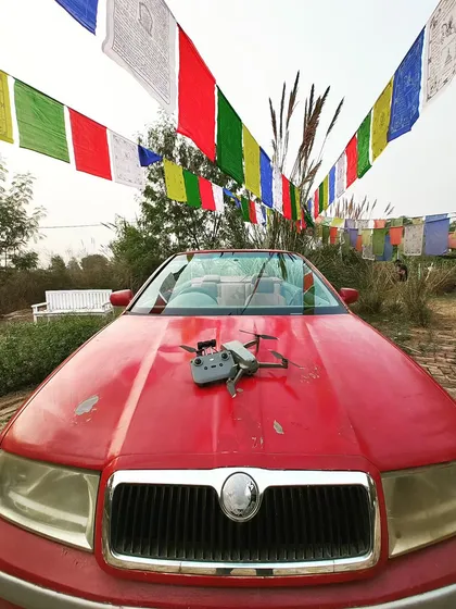 My DJI Air 2S drone ready for a pre-wedding shoot at The Picture Town. The vibrant prayer flags and classic car create a unique and colorful setting for a couple's story.