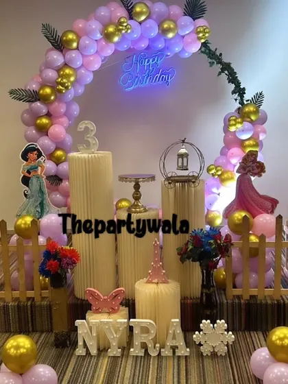 A beautiful princess theme for Nyra's 3rd birthday. The purple and gold balloon arch is accented with ivy, and the light-up name sign adds a warm glow to the setup.