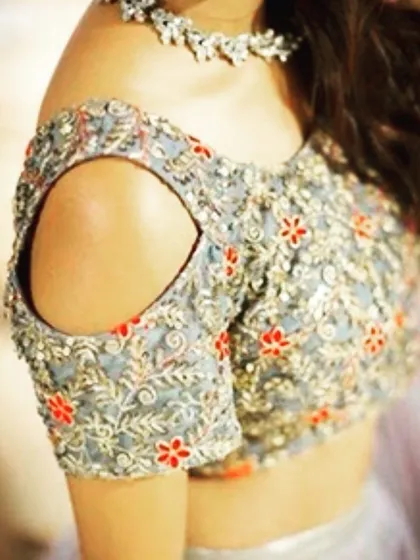 A modern cold-shoulder blouse design with floral embroidery. This cut is a stylish way to add a contemporary feel to any ethnic outfit.