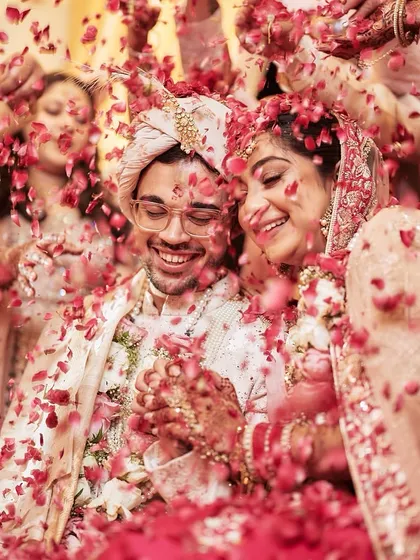 A shower of love. The couple is surrounded by family and friends, all showering them with petals in a moment of collective joy and blessing.