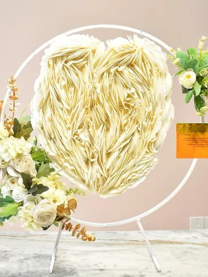 This is one of my specialty designs, a gravity-defying floating heart cake. The heart-shaped cake appears to float in mid-air, supported by a delicate stand and adorned with elegant white feathering and floral arrangements, creating a truly magical and unforgettable showstopper for any celebration.