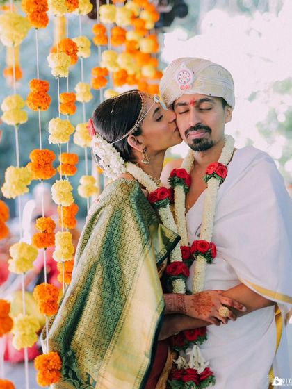 A sweet kiss on the cheek from the bride to her groom, a candid moment of affection.