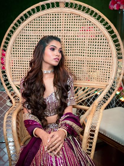 A regal pose in a peacock chair. The makeup is fit for a queen, with a strong eye look and perfectly sculpted features that command attention.